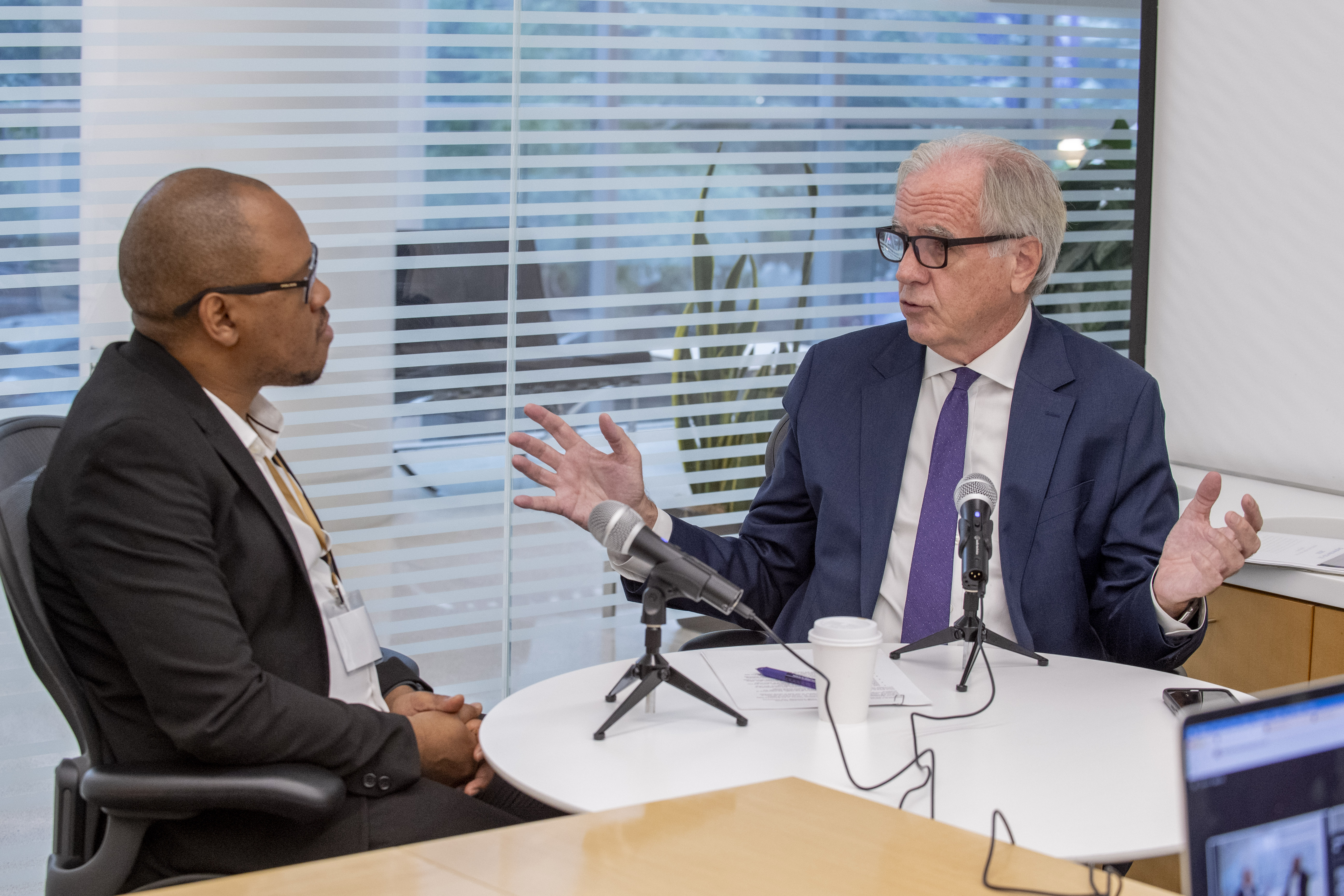 Two people sitting at a table recording a podcast