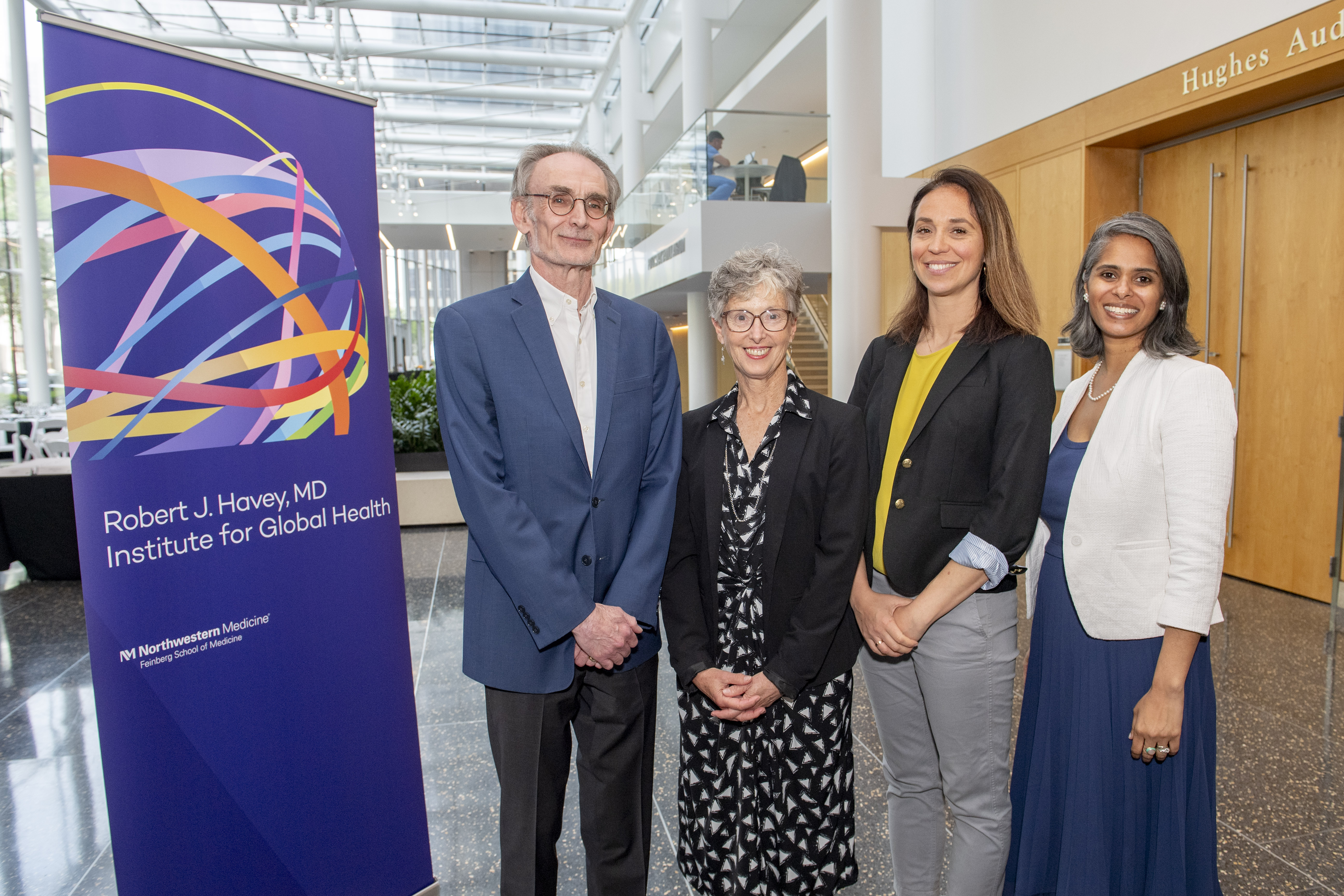 Keynote speakers and Center for Global Health Education co-directors stand next to the Havey Institute for Global Health banner