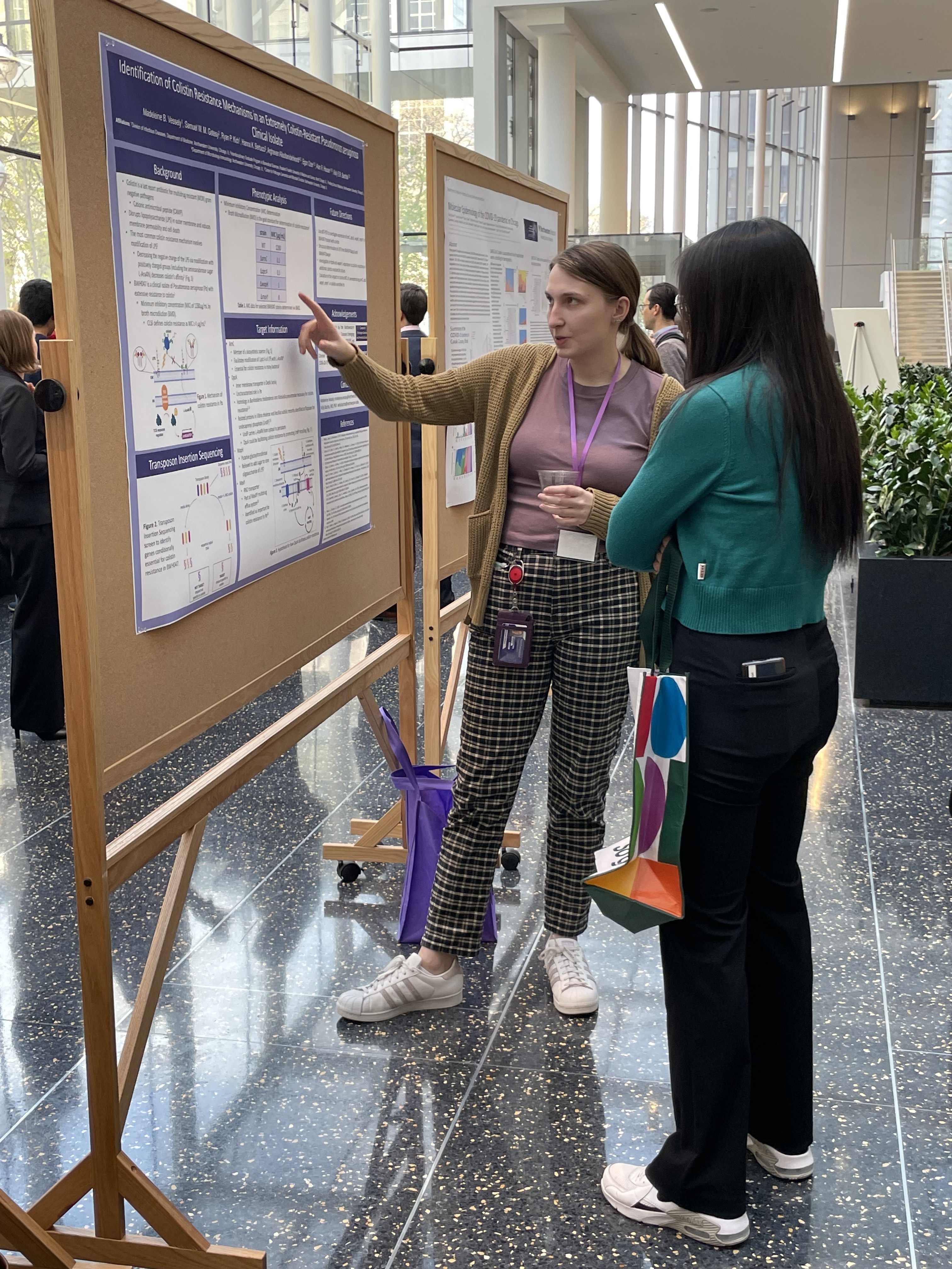 Symposium participant presenting their poster to an attendee