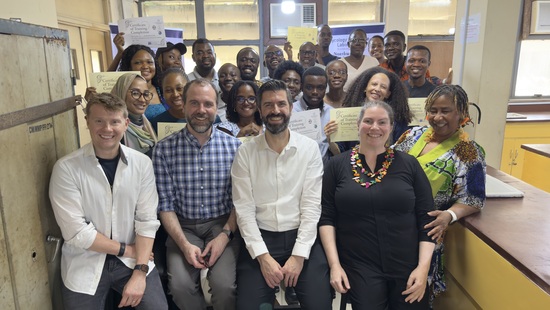 Large group of people smiling while sitting and standing in a laboratory