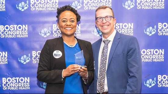 Juliet Lumati standing with a colleague and holding an award