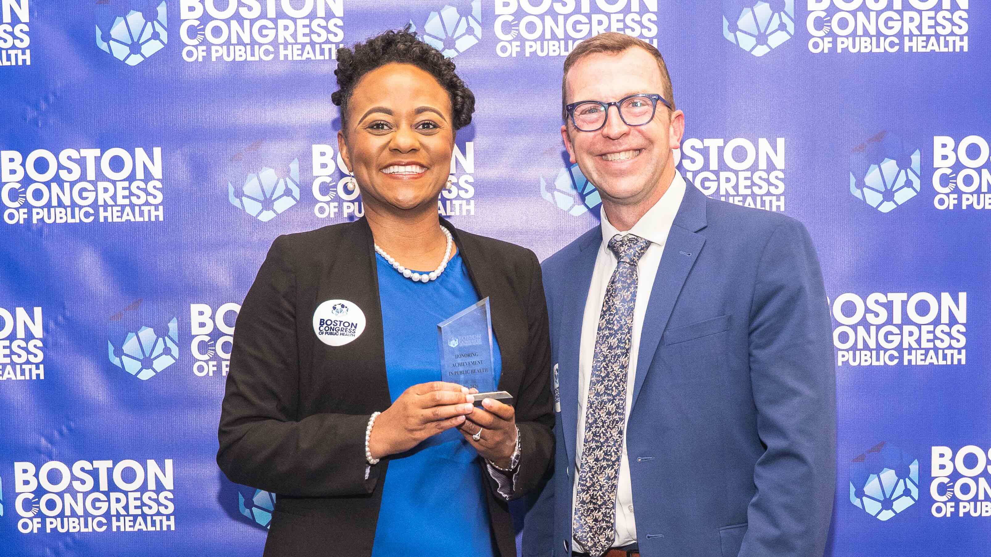 Juliet Lumati standing with a colleague and holding an award