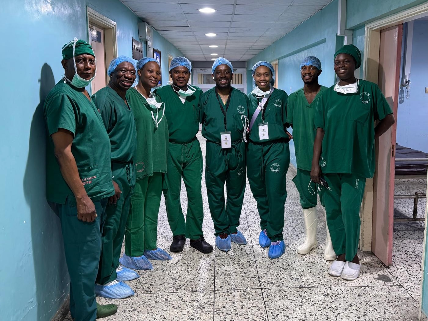 A group of surgeons in dark green scrubs standing in a hallway
