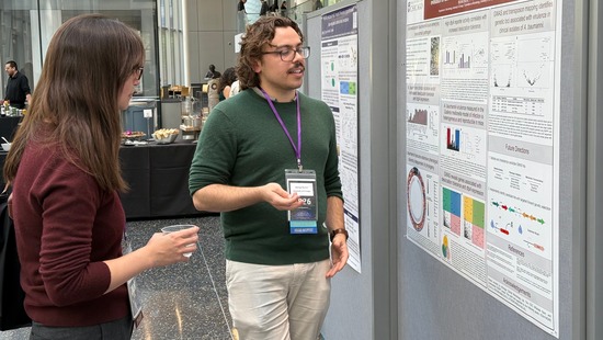 An event presenter sharing their poster presentation with an attendee in front of a poster